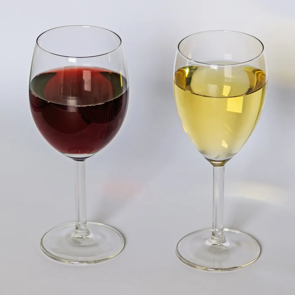 Ein Glas Weißwein und ein Glas Rotwein nebeneinander auf einem Tisch
