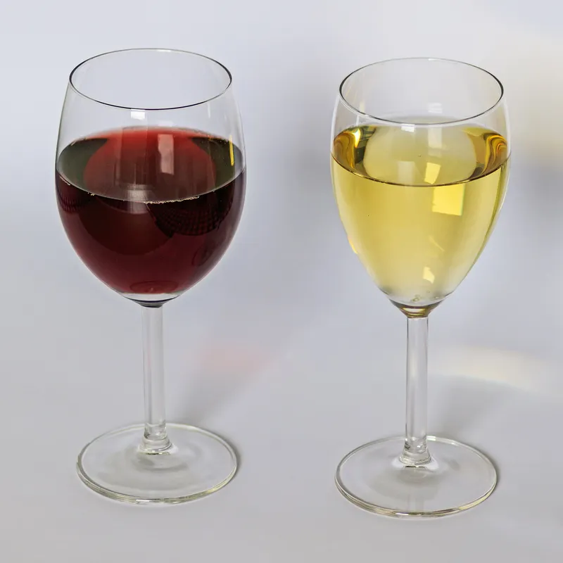 Ein Glas Weißwein und ein Glas Rotwein nebeneinander auf einem Tisch