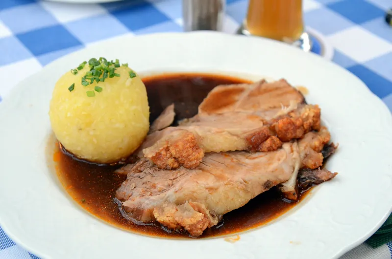 Angerichteter Schweinebraten mit Kartoffelknödeln auf dem Teller